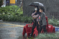 HUJAN LEBAT: Dua orang wanita menggunakan payung saat hujan lebat.
