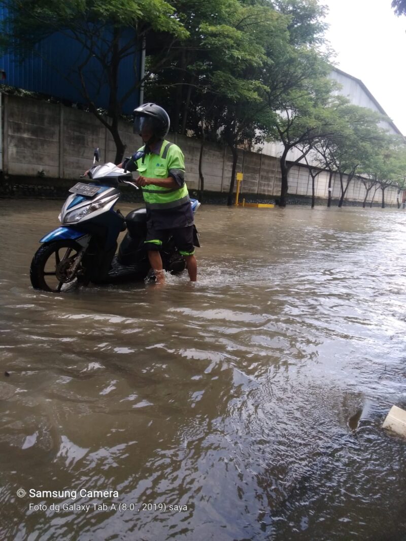 DORONG MOTOR: Salah seorang pengguna sepeda motor, mendorong kendaraannya akibat banjir di Kawasan Imdustri Olek Balaraja, Senin (18/03/2024).